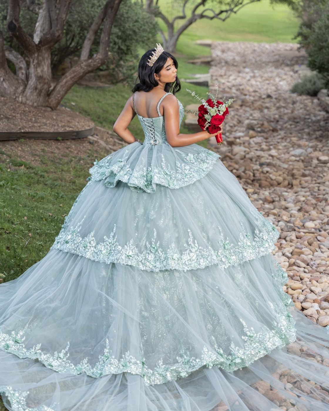 Quinceañera in a mint ball gown with a crown and red roses